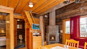 Acogedor interior de cabaña de troncos, con comedor, chimenea y baño.