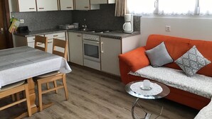 A compact kitchen with a dining area, a sofa, and a small table with a candle. - Apartment Adler by Interhome (Saas-Fee)