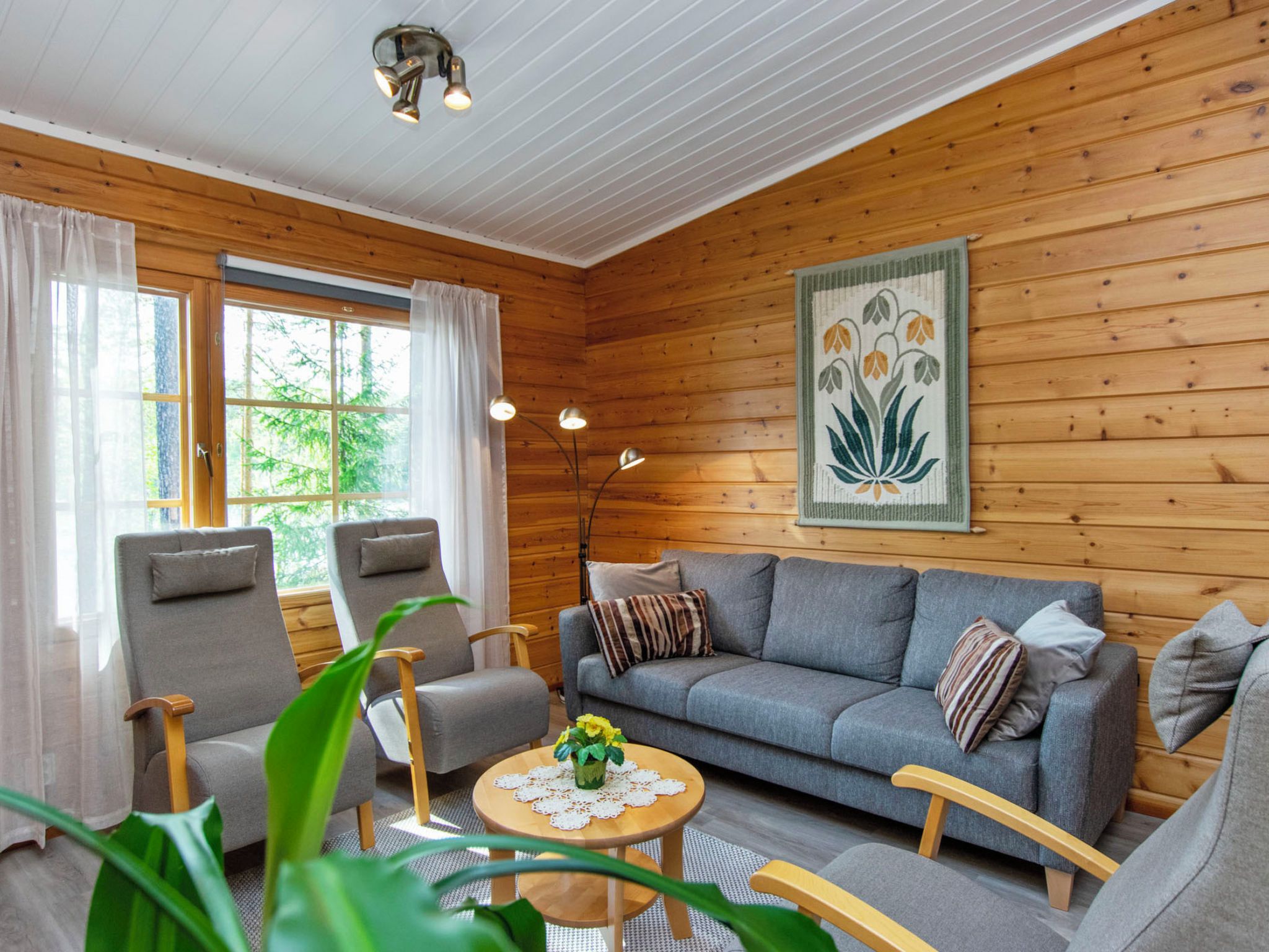 Un salon chaleureux avec un canapé, deux fauteuils, une table basse et un tableau accroché au mur.