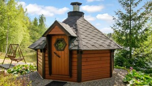 Eine kleine Holzhütte mit einer sechseckigen Tür, einem Schornstein und einer Schaukel in der Nähe.