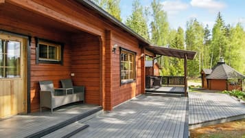 A wooden cabin with a deck, outdoor seating, and a small shed.