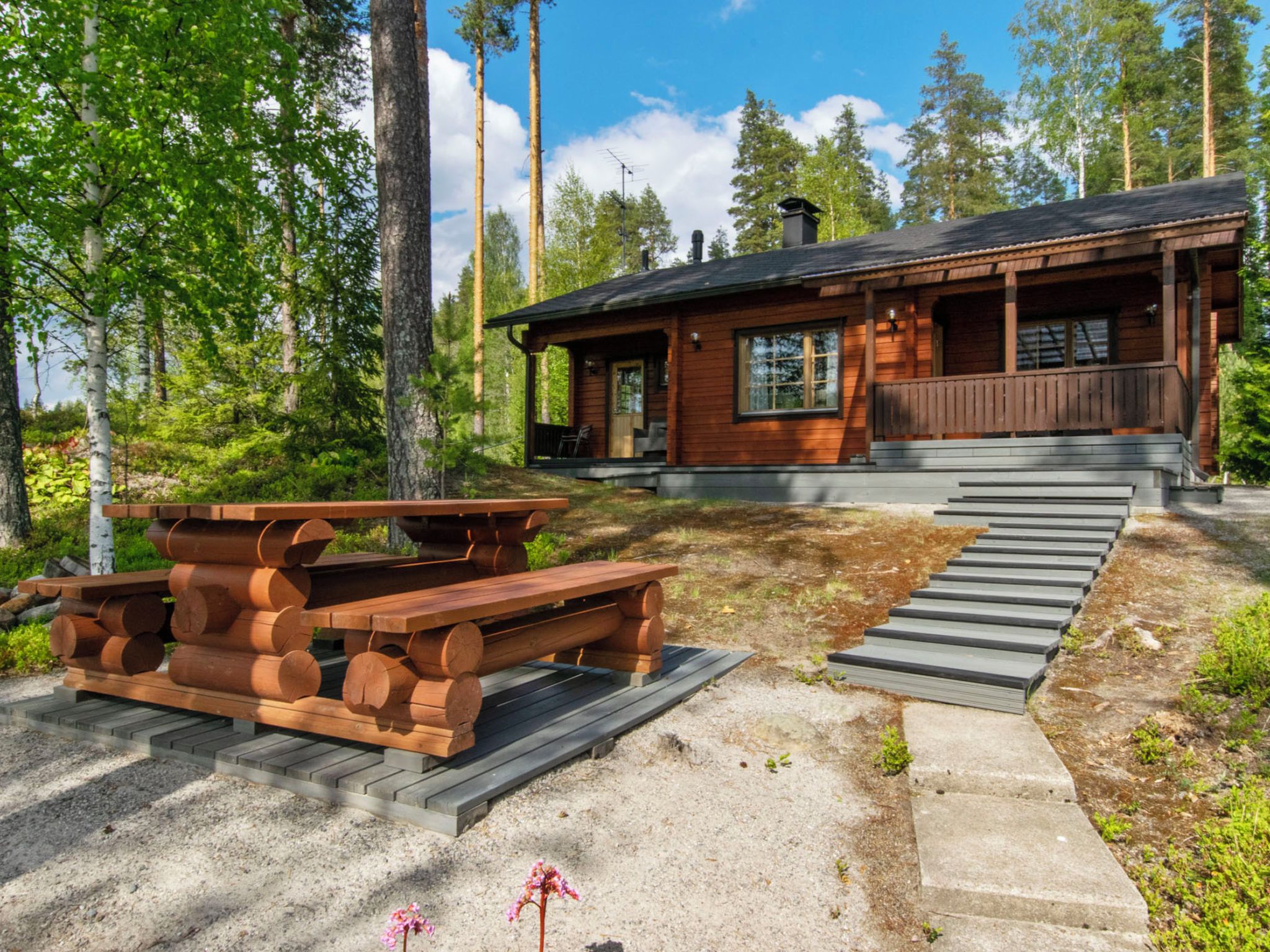 Een houten chalet met een veranda, een picknicktafel en een trap naar de ingang.