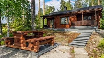 Een houten chalet met een veranda, een picknicktafel en een trap naar de ingang.