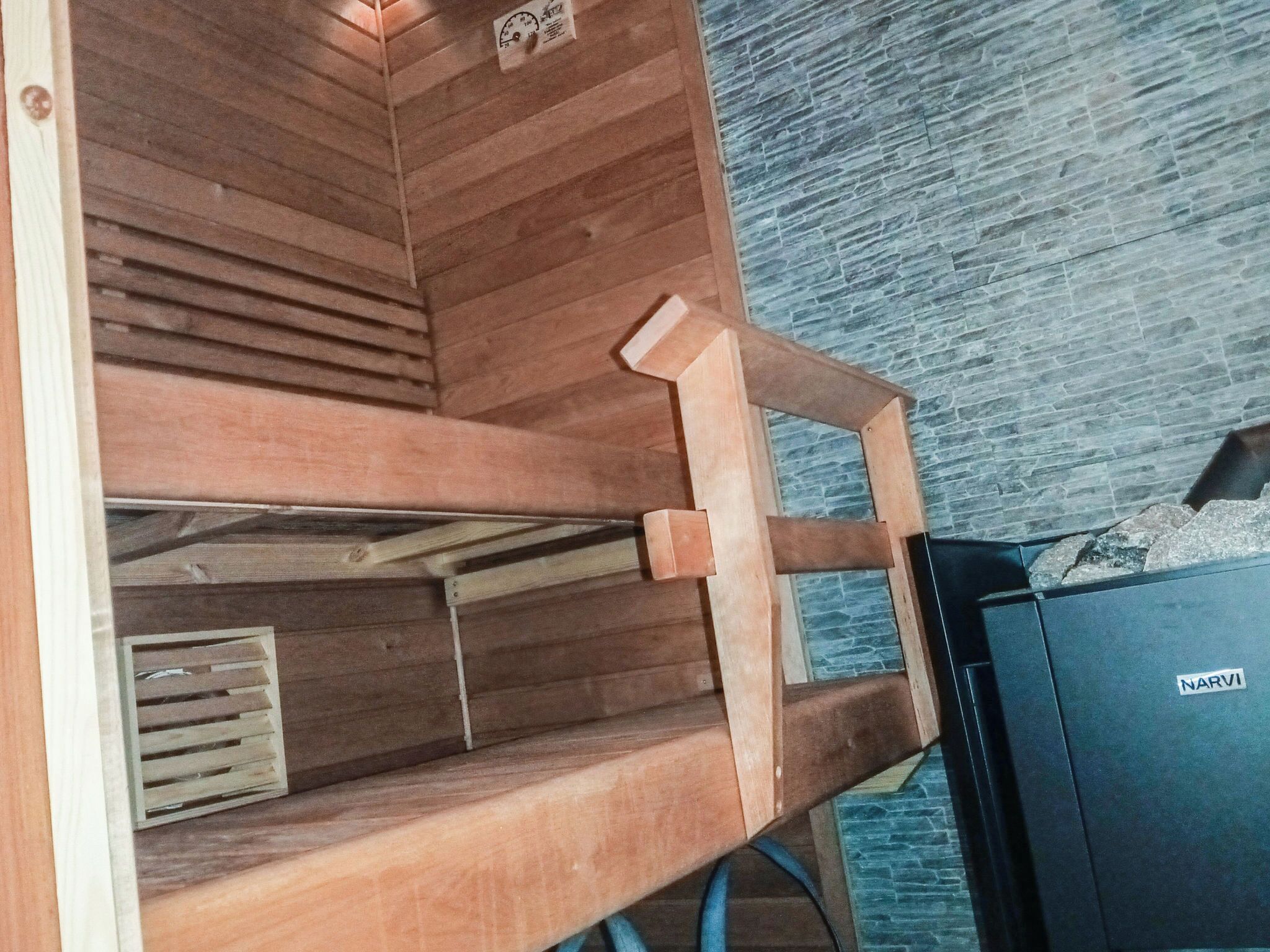 Een houten constructie met een latten plafond en een zwarte doos met de tekst 'NARVI' rechts.