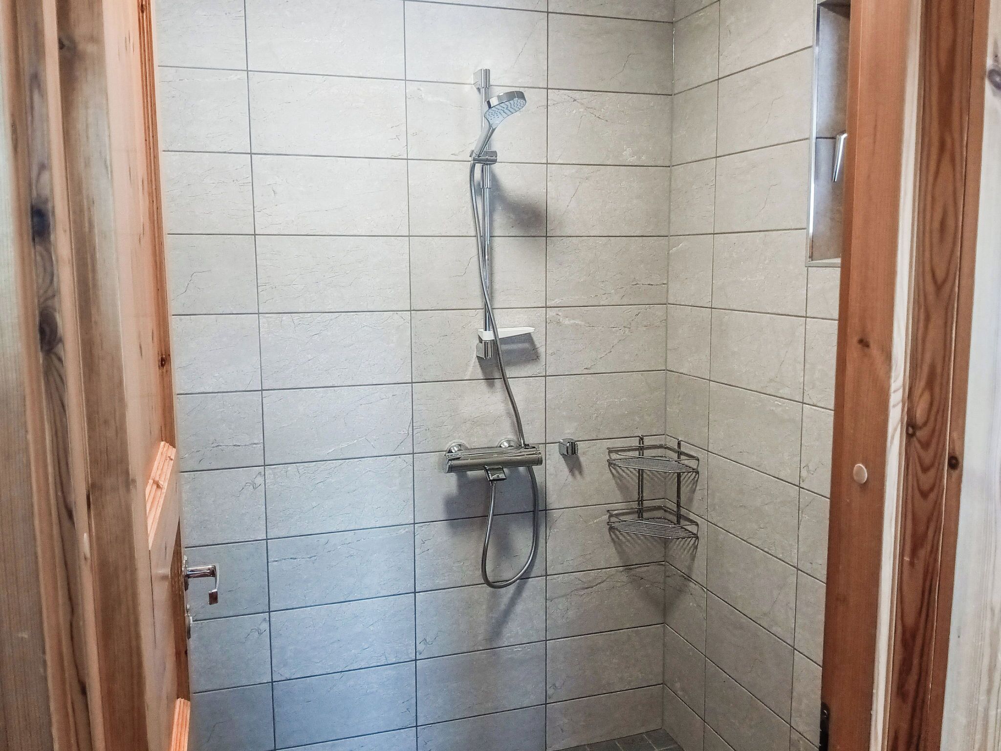 A small, tiled shower area with a handheld showerhead and a wall-mounted faucet.