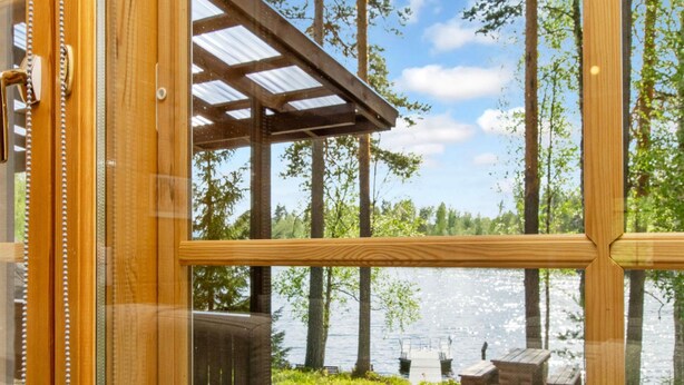 Eine Holzterrasse mit Blick auf einen See und Bäume.