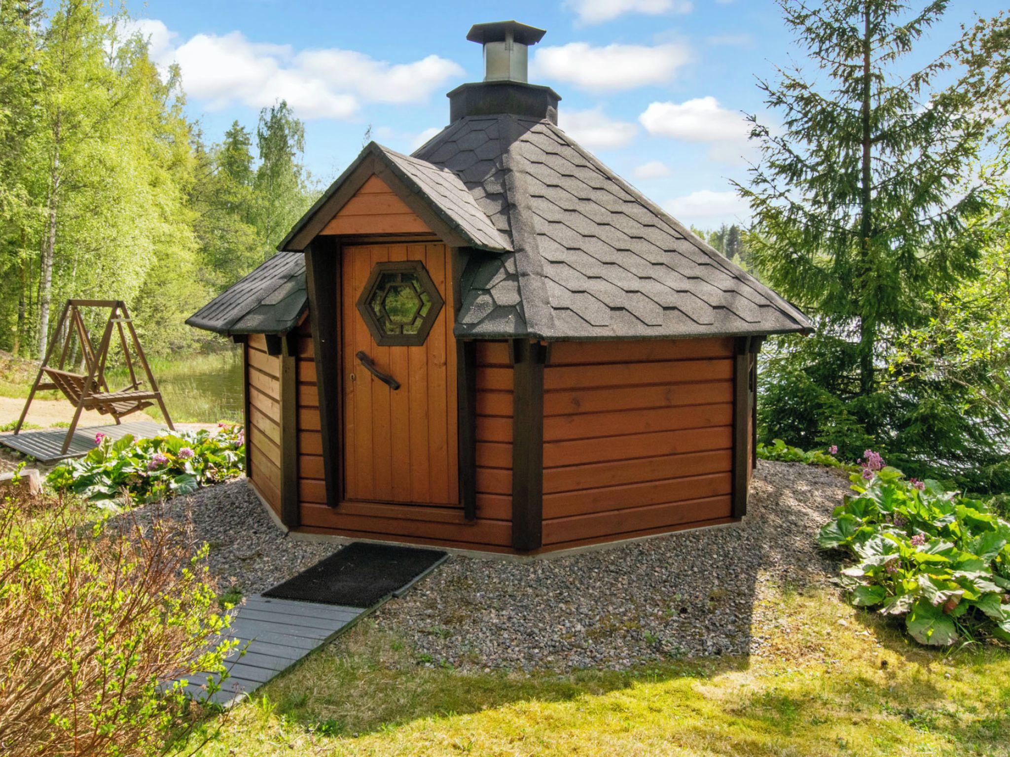 Een klein houten huisje met een schuin dak, een deur met een raam en een veranda.