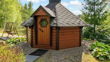 Een klein houten huisje met een schuin dak, een deur met een raam en een veranda.