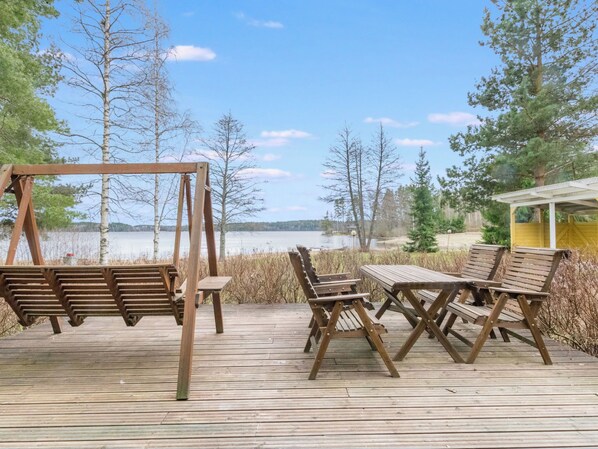 A wooden deck with a swing set and picnic table overlooking a lake.