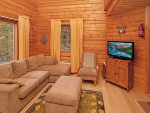 A cozy cabin interior with a sectional sofa, a small armchair, a television, and a fireplace. - Vacation home Kivelä by Interhome (Kuusamo)