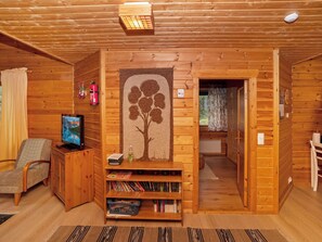 A cozy cabin interior with a television, bookshelves, a fireplace, and a door leading to another room.