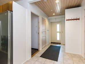 A hallway with a refrigerator, a door, and a coat rack.