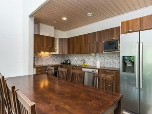 Une cuisine moderne avec des meubles en bois, un réfrigérateur en acier inoxydable et un pare-feu en carreaux.
