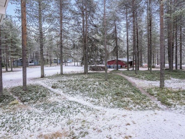 A snowy forest with a red cabin and a blue building.