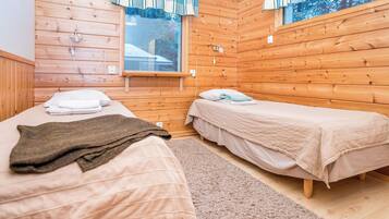 A cabin with two beds, wooden walls, a window, and a rug.