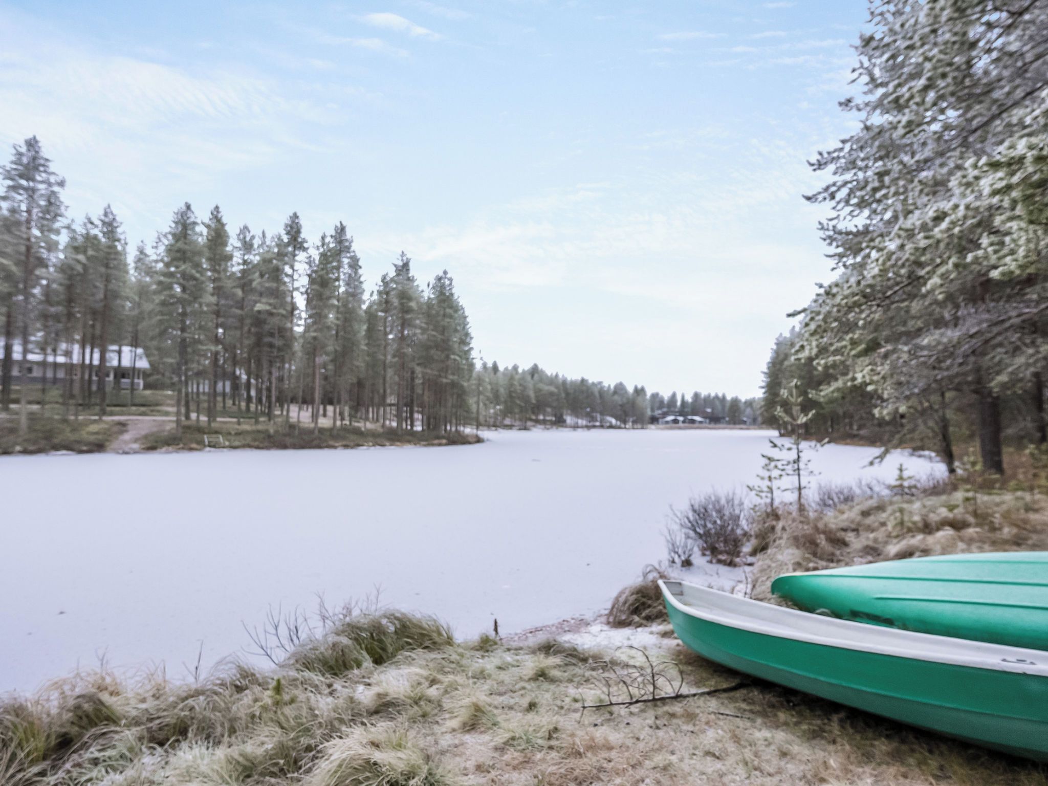 Ein See mit einer Baumreihe und einem Gebäude im Hintergrund.