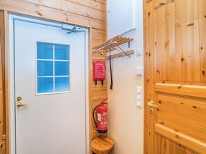 A wooden door with a window, a fire extinguisher, and a small stool. - Villa kuukkeli by Interhome (Kuusamo)