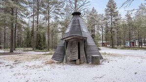 Eine kegelf örmige Holzkonstruktion in einer bewaldeten Gegend mit Schnee.