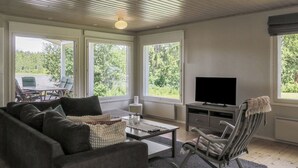 Un salon moderne avec un canapé, une table basse, un téléviseur et un fauteuil à bascule.