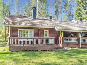 A log cabin with a tiled roof, a porch with railings, and a chimney. - Tahkon nipashonka 2 a by Interhome (Nilsiä)