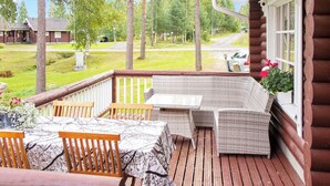 Eine Holzterrasse mit Korbmöbeln, einem Tisch und Stühlen.