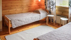 A small, cozy room with wooden walls, a single bed, a small stool, and a window with a view of greenery. - Pihlaja by Interhome (Hämeenlinna)