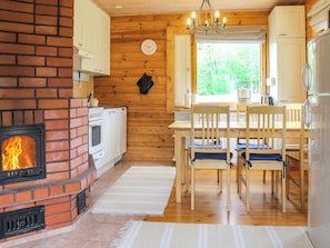 Una cocina acogedora con chimenea de ladrillo, armarios de madera y un comedor con sillas y mesa.
