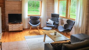 A cozy cabin interior with a wooden interior, a TV, two chairs, a sofa, and a window with a view of greenery. - Pihlaja by Interhome (Hämeenlinna)