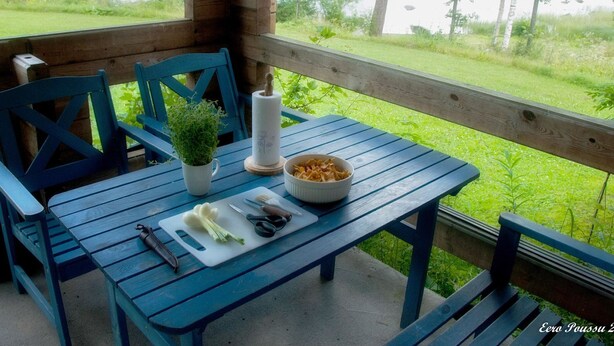 A wooden deck with a table set for a meal, overlooking a lake. - Pihlaja by Interhome (Hämeenlinna)