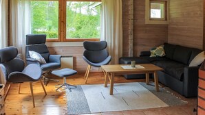 A cozy living room with a wooden interior, two armchairs, a sofa, a coffee table, and a view of greenery outside. - Pihlaja by Interhome (Hämeenlinna)