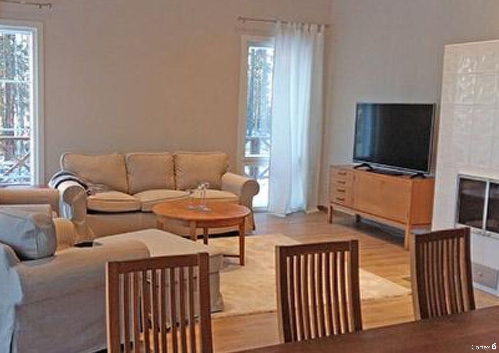 Een woonkamer met een bank, een salontafel, een televisie en een open haard.