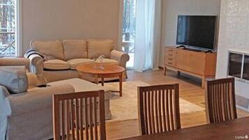 Een woonkamer met een bank, een salontafel, een televisie en een open haard.