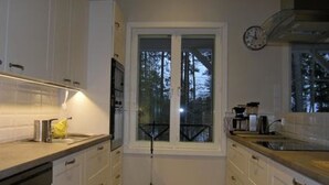A kitchen with white cabinets, a window, and a clock on the wall. - Ylä-hannala by Interhome (Muurame)