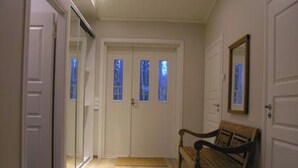 A hallway with a wooden bench, a door with a mirror, and a window with a view of trees. - Ylä-hannala by Interhome (Muurame)