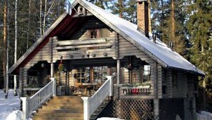 A log cabin with a porch and steps leading up to the entrance.