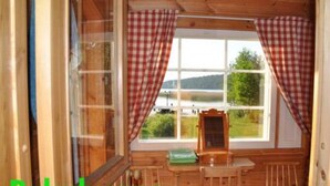 A wooden cabin interior with a window, a table, and two chairs.