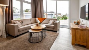 A modern living room with a beige sofa, a round coffee table, and a wooden cabinet. - Green Resort Mooi Bemelen by Interhome (Bemelen)