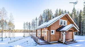 A wooden cabin with a porch and a small deck, surrounded by snow and trees. - Vacation home Inkeri by Interhome (Jämsä)