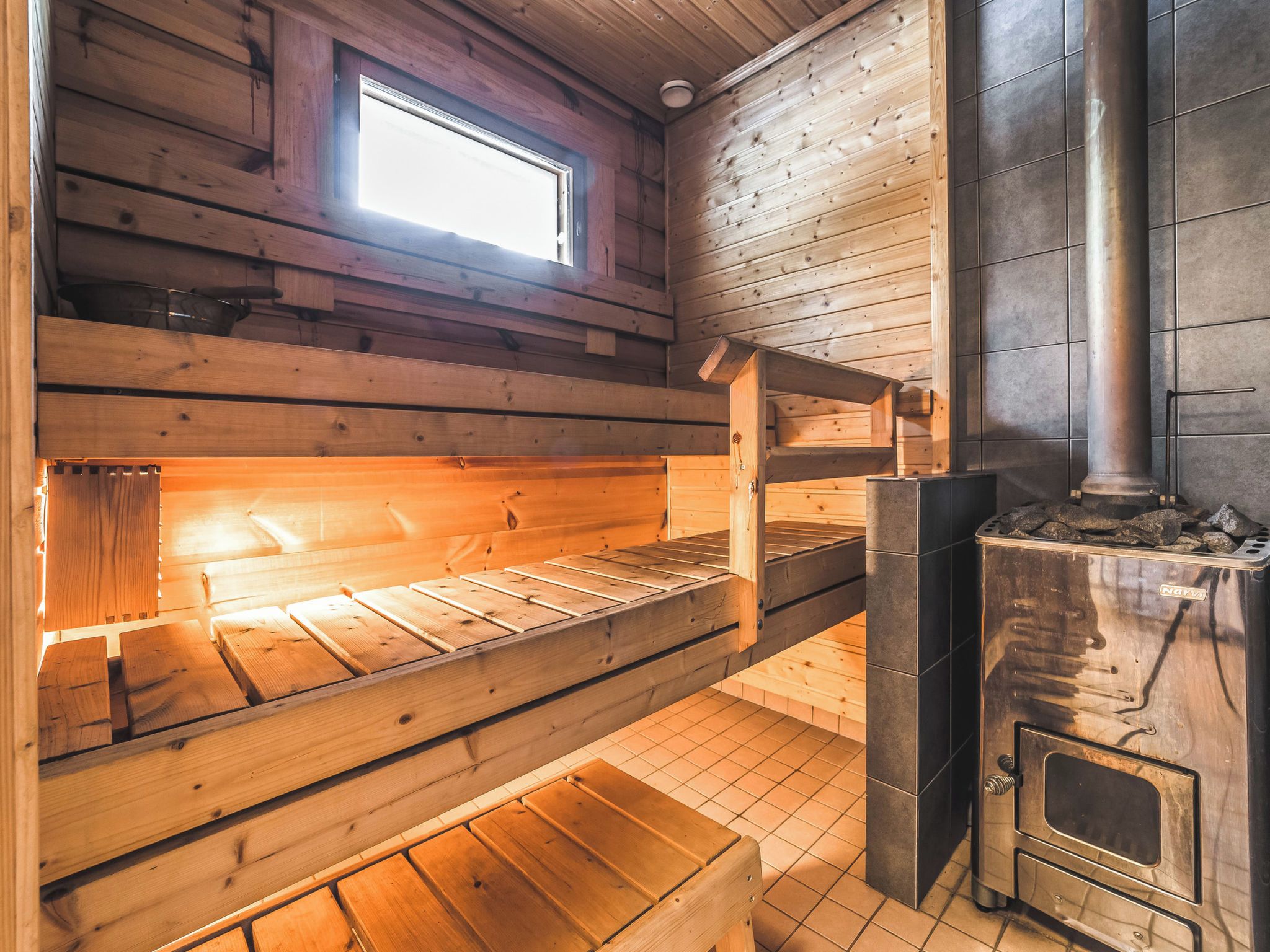 A wooden cabin with a bunk bed, a fireplace, and a window.