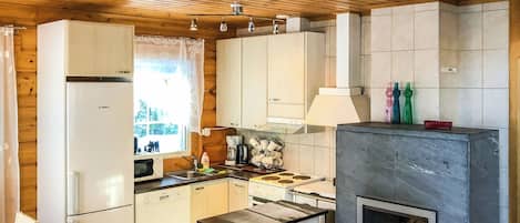Een keuken met houten plafond, witte kasten, een fornuis en een inbouwplaats voor een open haard.