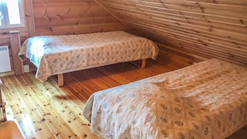 Mökki, jossa on kaksi sänkyä, puulattiat ja ikkuna.