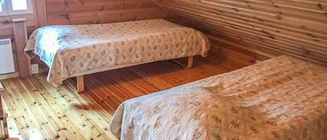 A cabin with two beds, wooden floors, and a window.