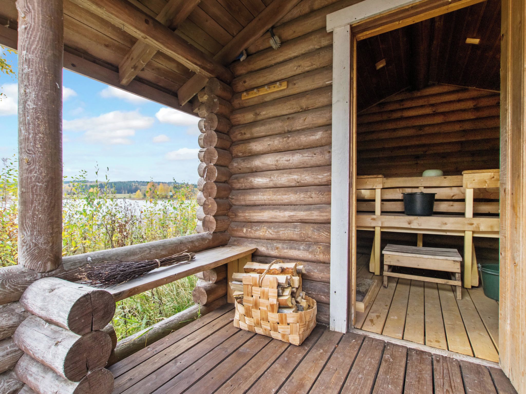 A wooden cabin with a porch, a bench, and a stack of firewood.