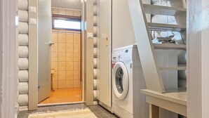Ein Waschraum mit Waschmaschine, Wäscheständer und einer Holztür zu einem Badezimmer.