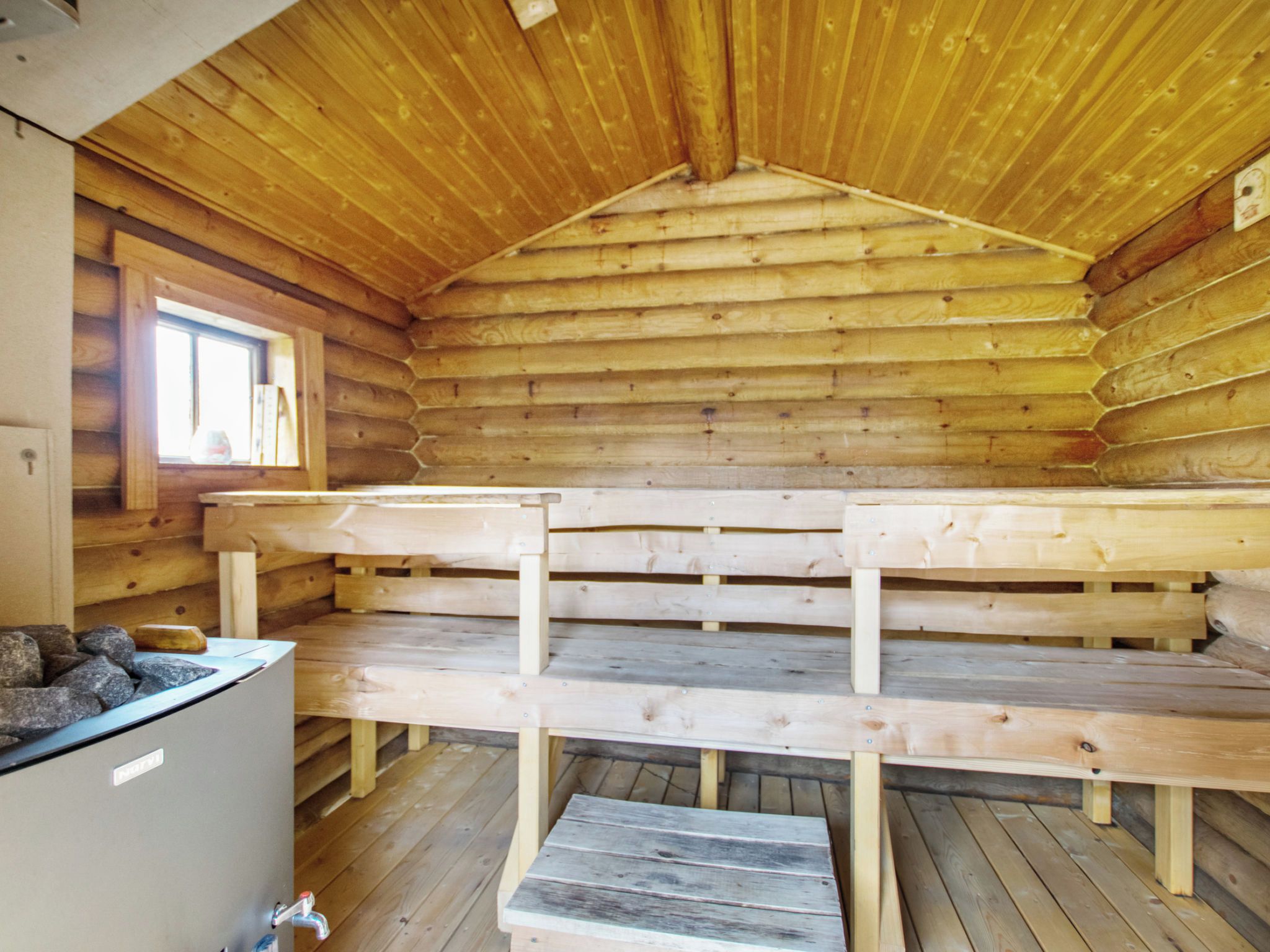 Een vakantiehuisje van binnen, met een houten bank en een kleine tafel.