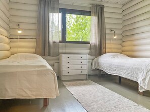 Une chambre de style cabane avec deux lits, une commode et une fenêtre avec des rideaux.