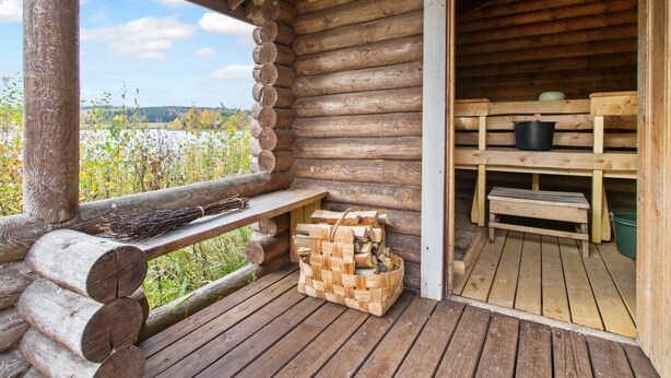 Eine Holzhütte mit Veranda, einer Bank und einem Holzstapel.