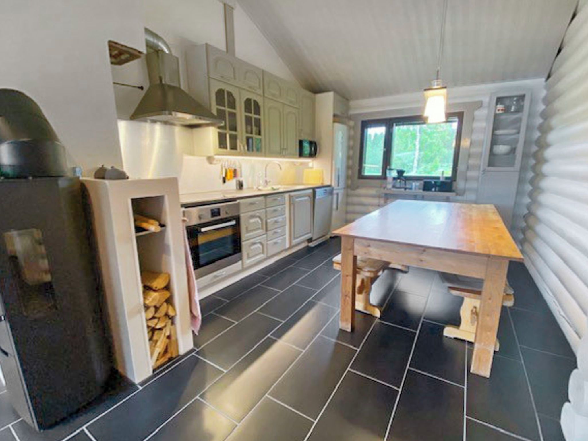 Una cucina moderna con isola centrale, forno integrato e un'ampia finestra che offre luce naturale.