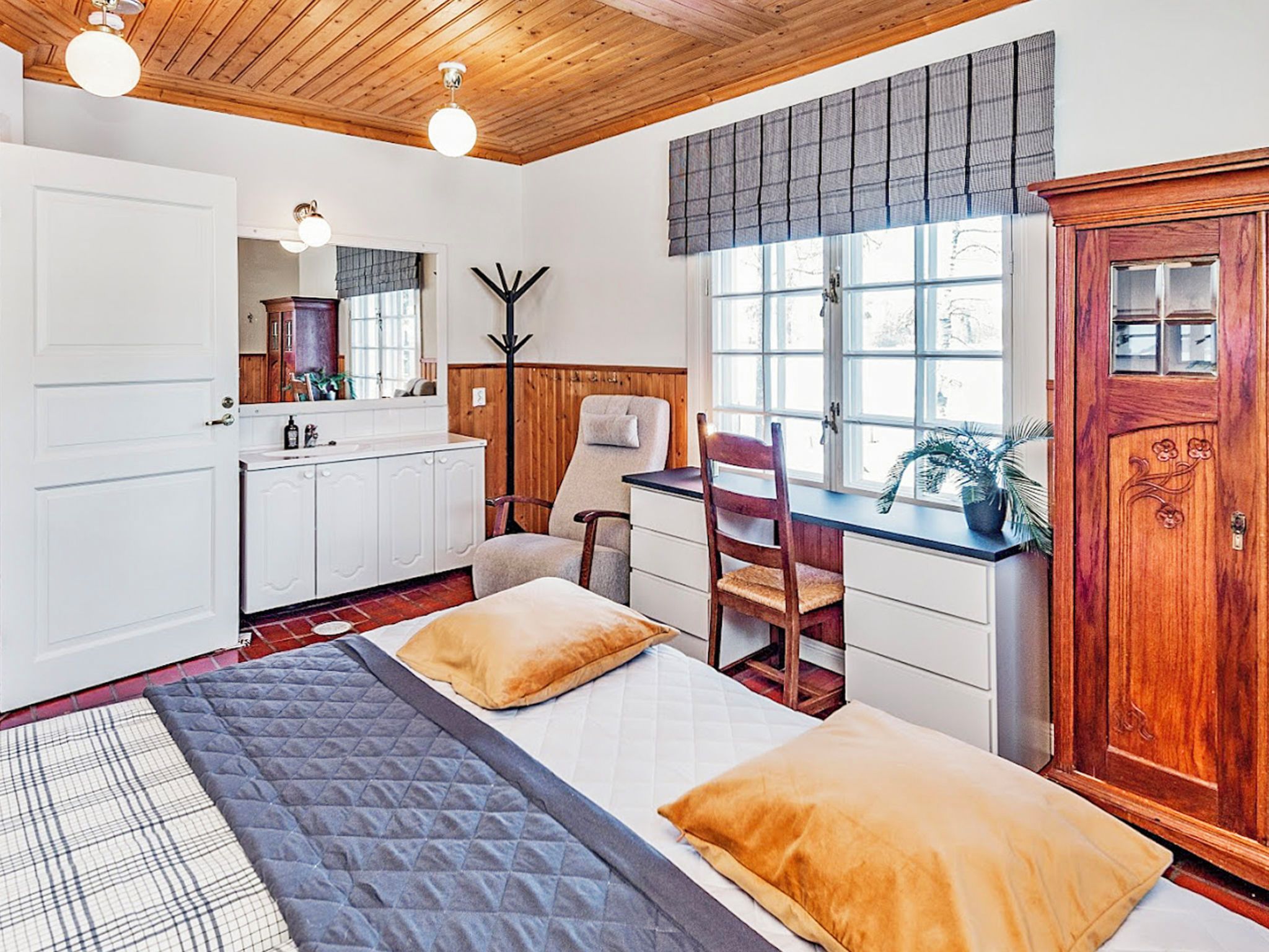A room with a bed, a desk, a chair, a wardrobe, and a window.