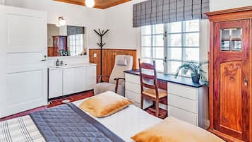 A room with a bed, a desk, a chair, a wardrobe, and a window.